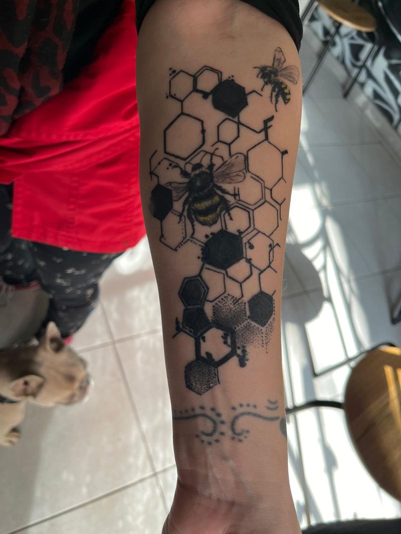 Blackwork honeycomb forearm piece with two bees picked out in yellow