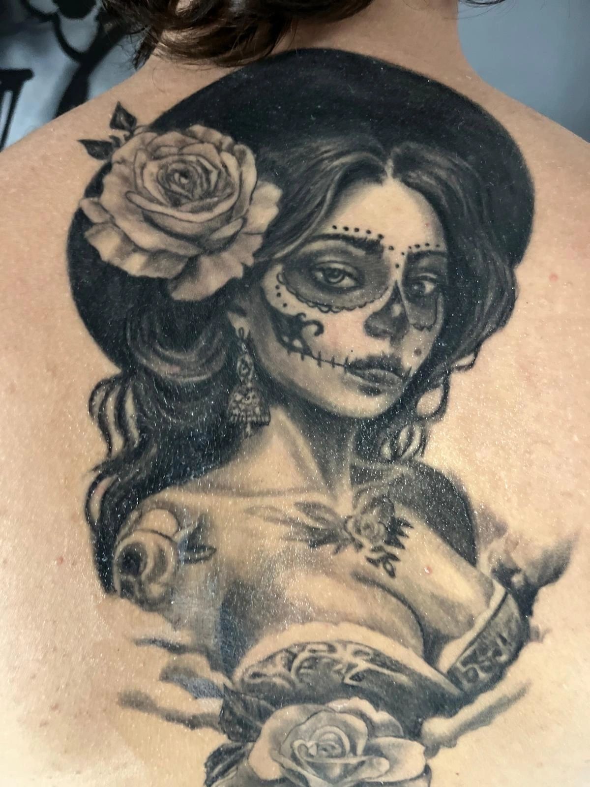 Black and grey realism portrait of La Catrina with roses, covering a full back